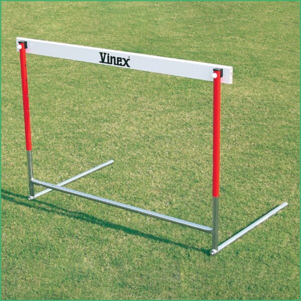 Red and gray track hurdle on a grassy field