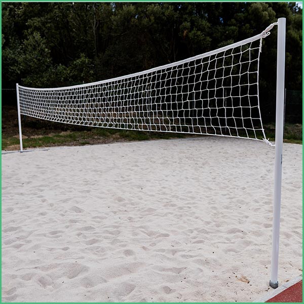 Beach volleyball net set up on a sandy court with trees in the background