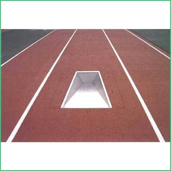 Red running track with white lane lines and a rectangular open pit in the center lane, showing interior sloped walls and bright interior light