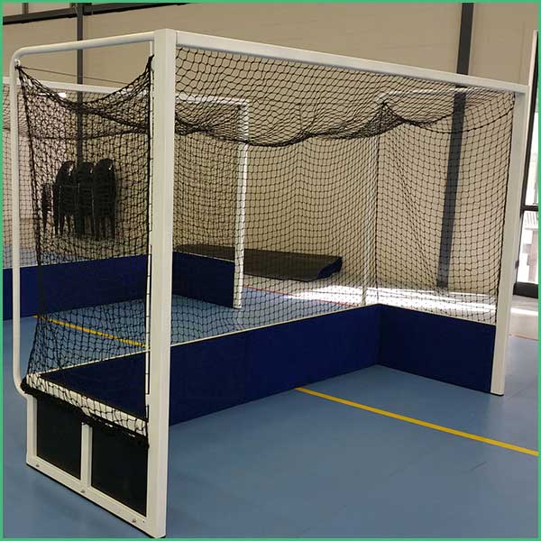 Indoor practice goal with white frame and black netting inside a padded blue enclosure on a gym floor