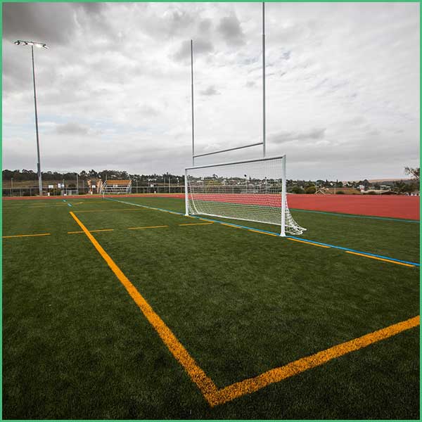 Soccer goal on a synthetic turf field with yellow and blue markings and an empty track in the background 