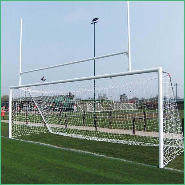 Soccer goal on a grassy field with a white frame and net; players and equipment visible in the background