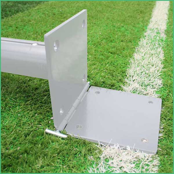 Metal base plate and vertical support anchored to a sports goal on grass near a white line mark