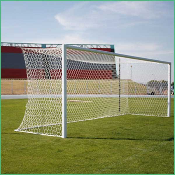 Soccer goal on a grassy field with a red building in the background under a blue sky
