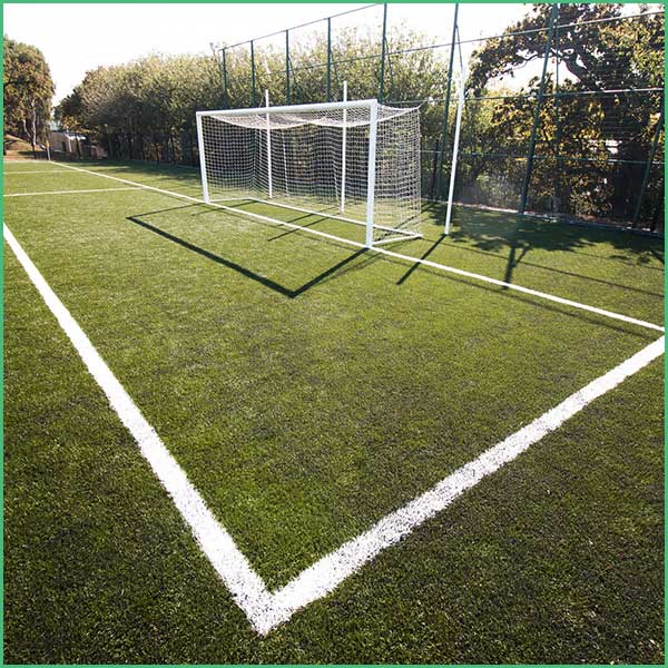 Soccer goal on artificial turf with white boundary lines and a surrounding fence