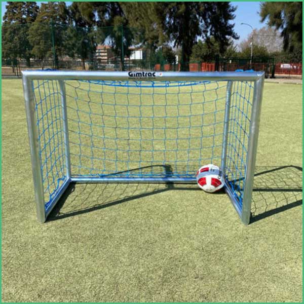 Blue framed soccer goal on a grassy field with a red and white ball resting inside the net
